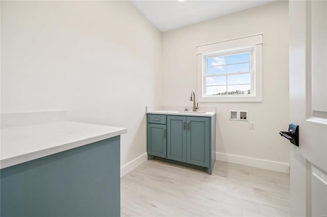 laundry area with hookup for a washing machine, cabinet space, baseboards, and a sink