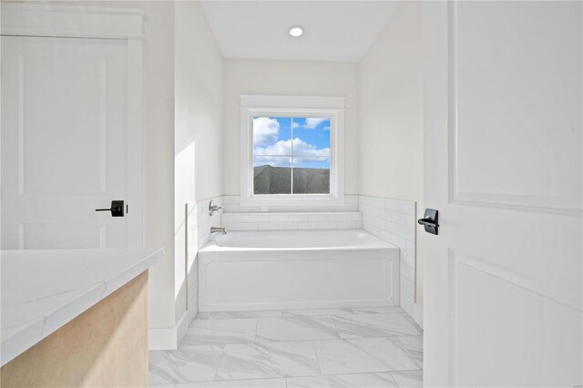 bathroom with marble finish floor and a bath