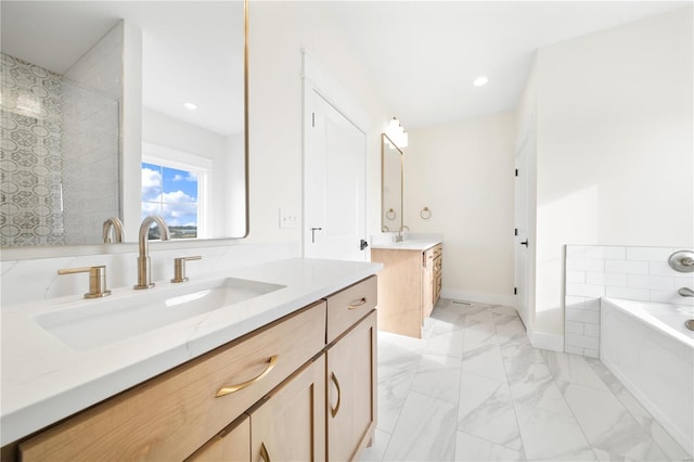 bathroom with recessed lighting, marble finish floor, a garden tub, and a sink