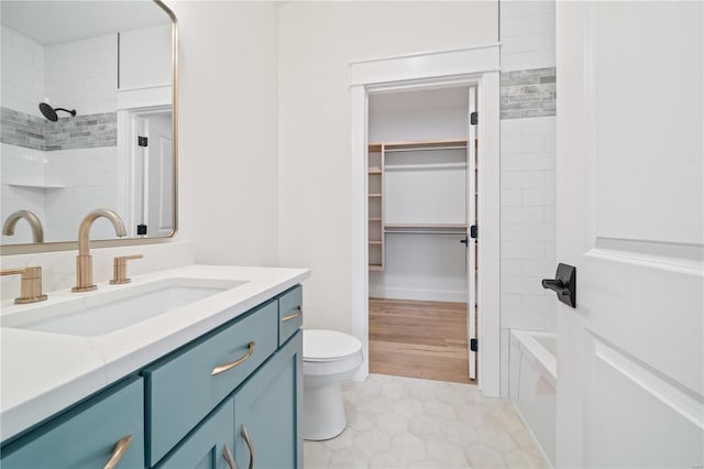 bathroom featuring shower / bathing tub combination, vanity, toilet, and a walk in closet