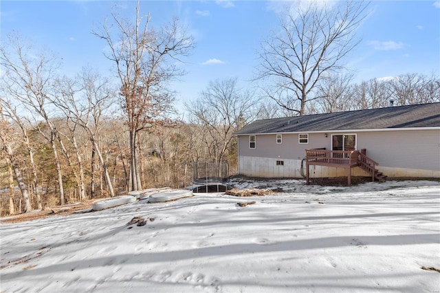 view of snowy exterior featuring a deck and a trampoline