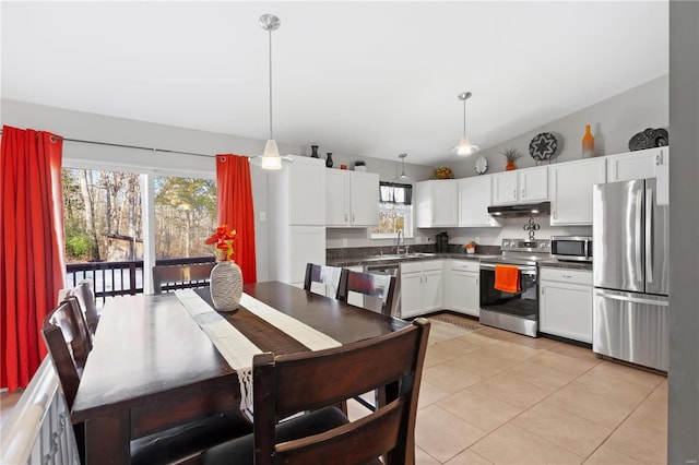 kitchen featuring stainless steel appliances, vaulted ceiling, hanging light fixtures, and white cabinets