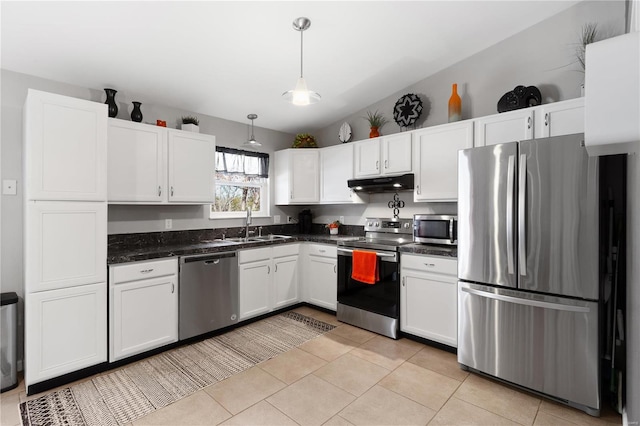 kitchen featuring lofted ceiling, light tile patterned floors, appliances with stainless steel finishes, white cabinetry, and decorative light fixtures