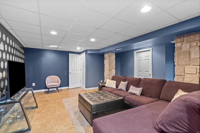 living room featuring decorative columns and a drop ceiling