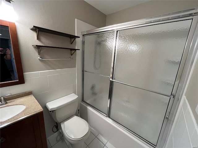 full bathroom with tile patterned floors, toilet, tile walls, vanity, and enclosed tub / shower combo