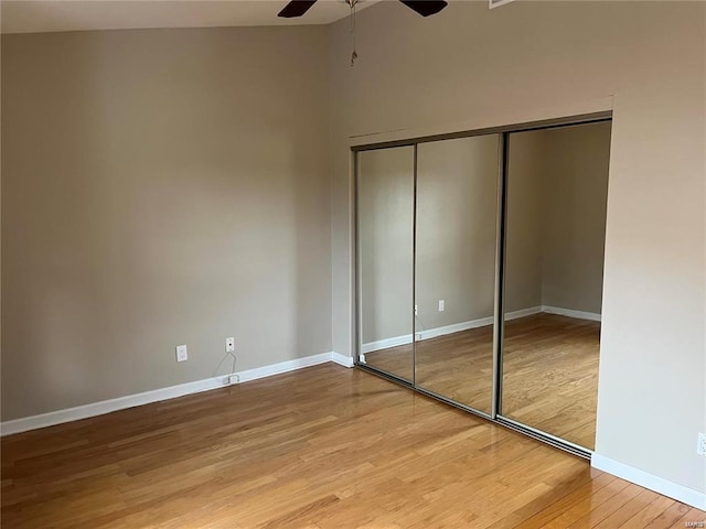 unfurnished bedroom featuring hardwood / wood-style floors, a closet, and ceiling fan