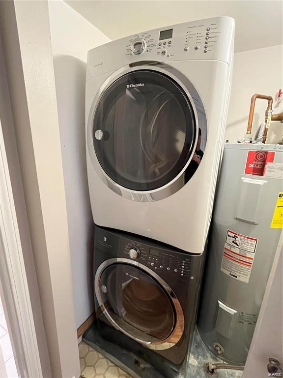 clothes washing area featuring water heater and stacked washer and dryer