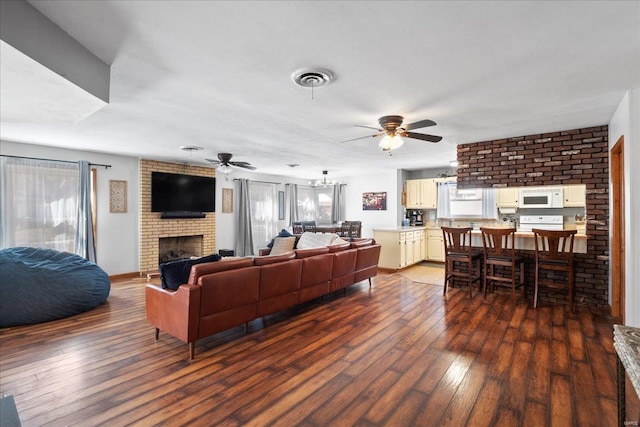 living room with dark hardwood / wood-style floors, ceiling fan, and a fireplace