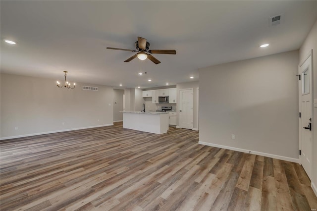 unfurnished living room featuring sink, ceiling fan with notable chandelier, and light wood-type flooring