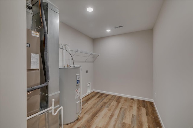 washroom featuring hookup for an electric dryer, electric water heater, and light wood-type flooring