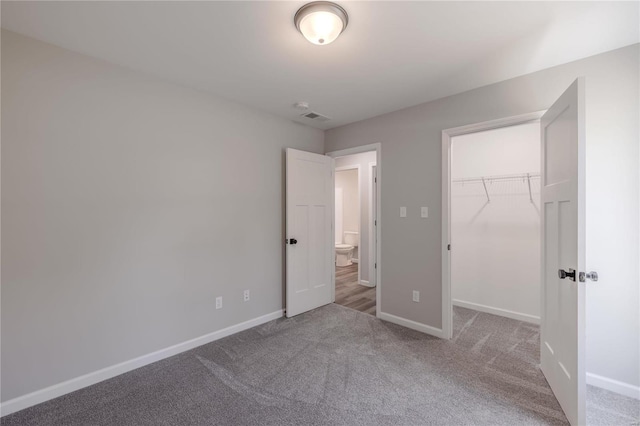 unfurnished bedroom featuring a closet, carpet flooring, and a spacious closet