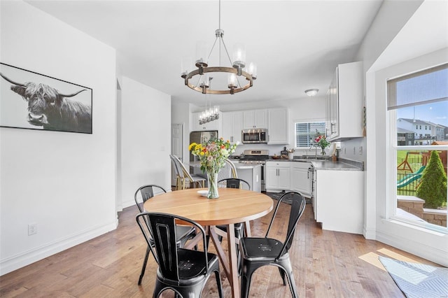 dining space with an inviting chandelier, sink, and light wood-type flooring