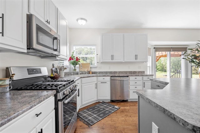 kitchen featuring sink, light wood-type flooring, white cabinets, and appliances with stainless steel finishes