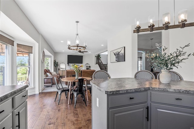 dining space featuring ceiling fan with notable chandelier and dark wood-type flooring