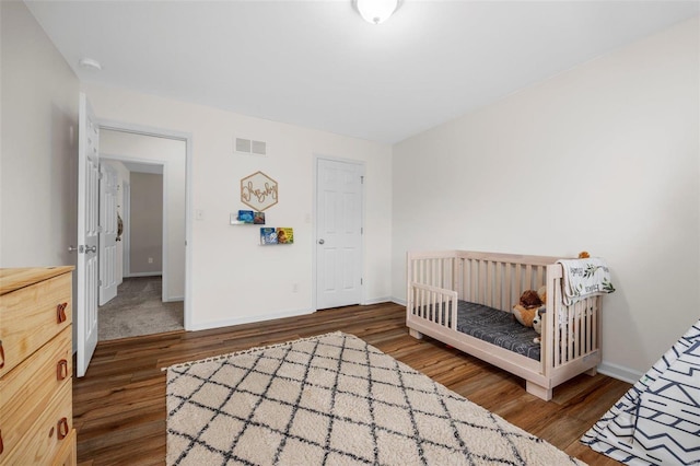 bedroom featuring a crib and dark hardwood / wood-style flooring