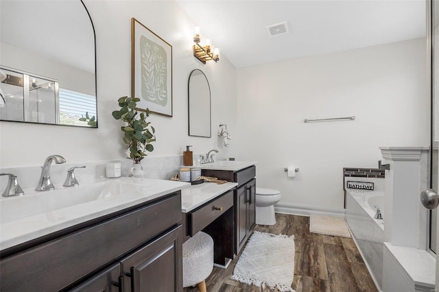 bathroom with vanity, a bath, hardwood / wood-style flooring, and toilet