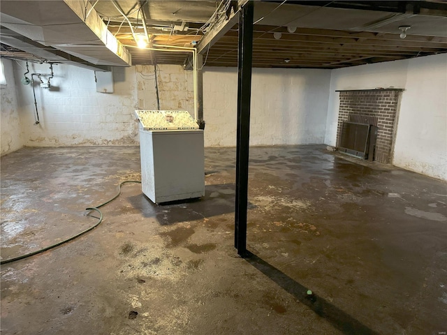 basement with refrigerator, electric panel, and a brick fireplace