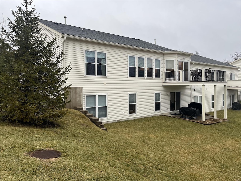 rear view of property with a yard and a balcony