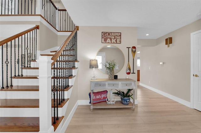 stairway featuring recessed lighting, wood finished floors, and baseboards