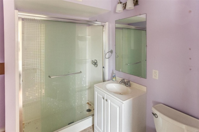 bathroom featuring toilet, vanity, and a shower with shower door