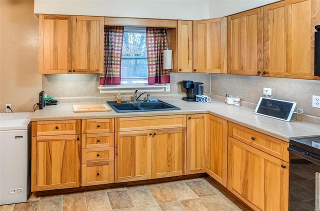 kitchen featuring tasteful backsplash, fridge, sink, and black electric range