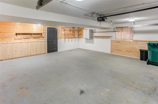 garage featuring a garage door opener and wooden walls