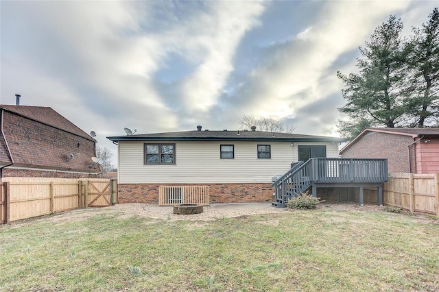 back of property featuring a yard, a deck, and a fire pit