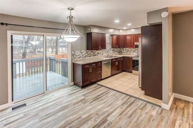 kitchen with pendant lighting, tasteful backsplash, light stone counters, stainless steel appliances, and light wood-type flooring