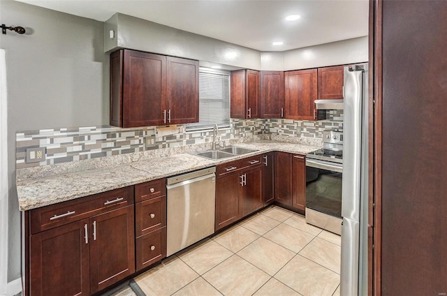 kitchen with sink, light tile patterned floors, appliances with stainless steel finishes, light stone countertops, and decorative backsplash