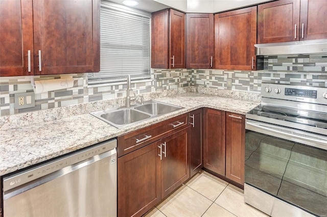 kitchen with sink, light tile patterned floors, stainless steel appliances, light stone countertops, and backsplash