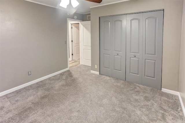 unfurnished bedroom featuring crown molding, light carpet, ceiling fan, and a closet