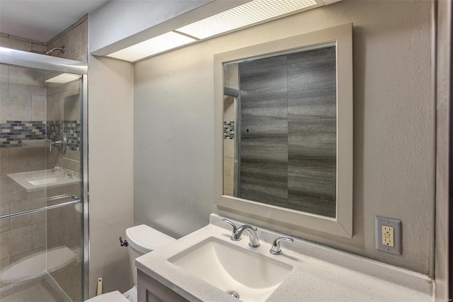 bathroom with vanity, a shower with shower door, and toilet