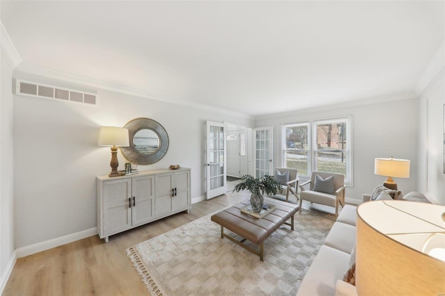 living room featuring crown molding, light wood-type flooring, and french doors