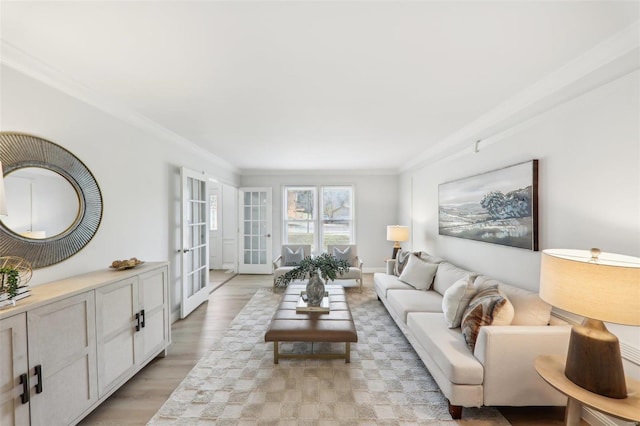 living room featuring light hardwood / wood-style flooring, ornamental molding, and french doors