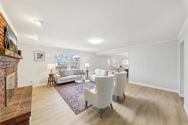 living room with ornamental molding, a brick fireplace, and light hardwood / wood-style flooring