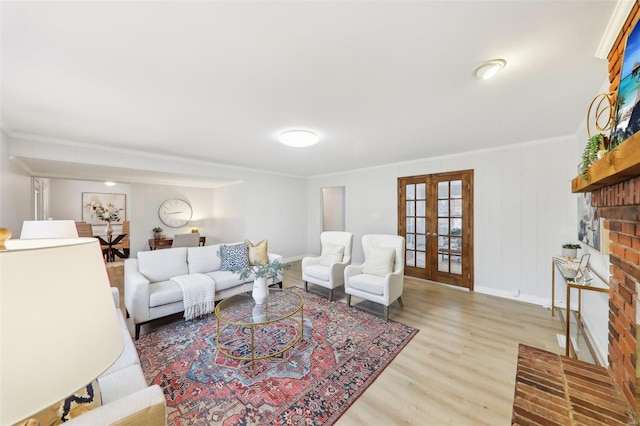 living room with crown molding, a brick fireplace, hardwood / wood-style floors, and french doors