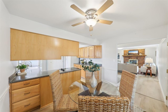 dining area featuring ceiling fan, a fireplace, and light hardwood / wood-style flooring