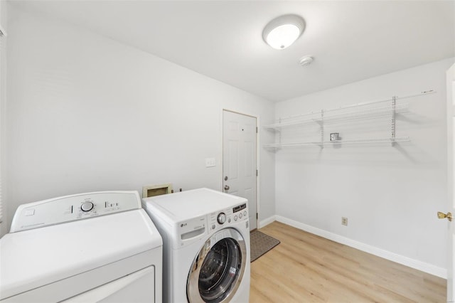 laundry room featuring washing machine and clothes dryer and light wood-type flooring