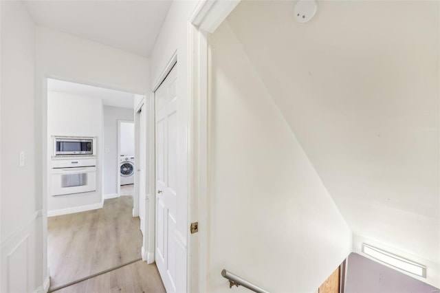 hallway with washer / clothes dryer and light wood-type flooring