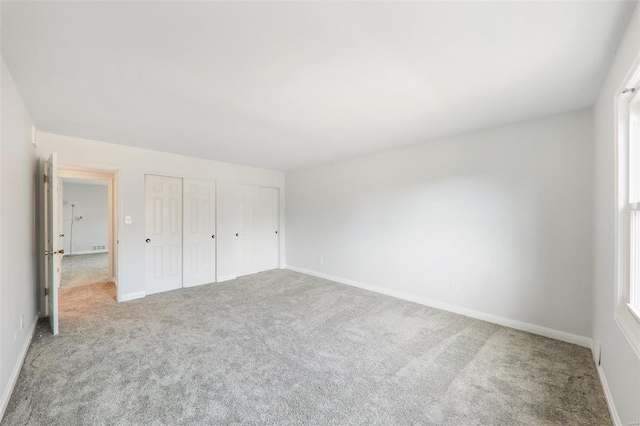 unfurnished bedroom featuring two closets and light carpet