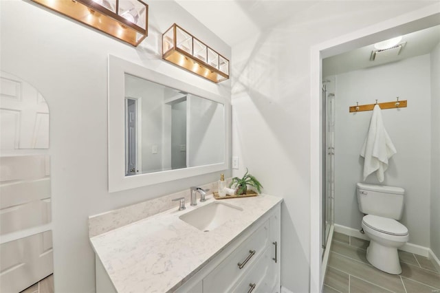 bathroom featuring vanity, toilet, tile patterned floors, and a shower with shower door