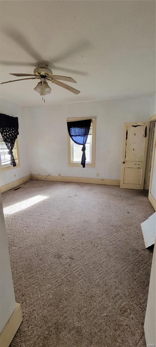 carpeted spare room with ceiling fan