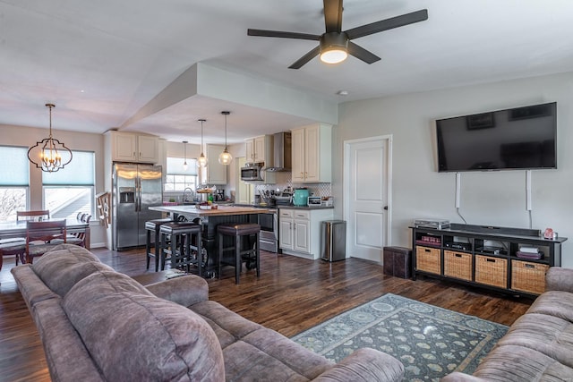 living room with ceiling fan with notable chandelier, lofted ceiling, dark hardwood / wood-style flooring, and sink