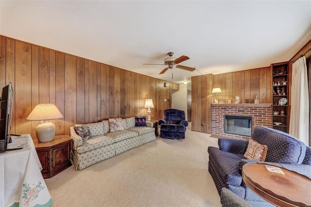 carpeted living room featuring a fireplace, ceiling fan, and wood walls