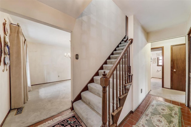 stairs featuring carpet flooring and a notable chandelier