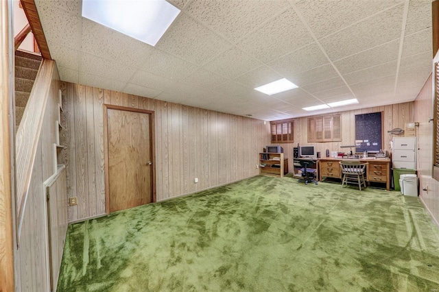 unfurnished office with a paneled ceiling, carpet flooring, and wood walls