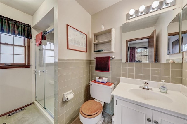 bathroom featuring vanity, toilet, a shower with shower door, and tile walls