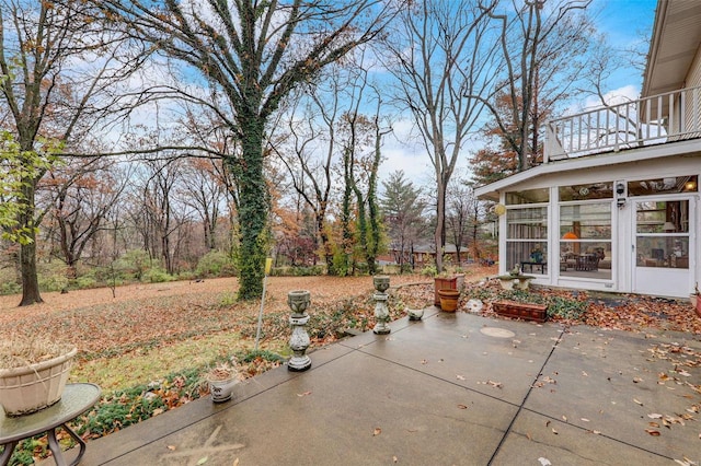 view of patio featuring a sunroom and a balcony