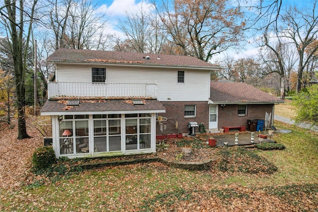 rear view of house with a yard, a patio area, and a sunroom