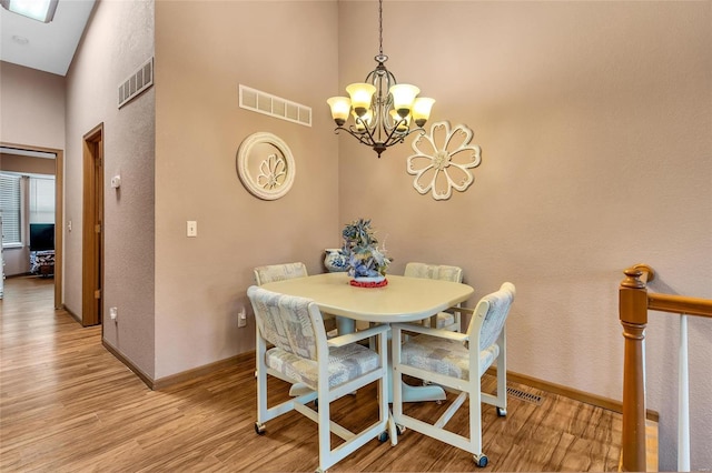 dining space featuring light hardwood / wood-style floors, a high ceiling, and a notable chandelier